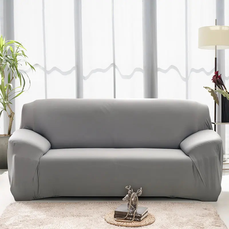 Housse de canapé extensible unie NEWTON gris foncé dans un salon